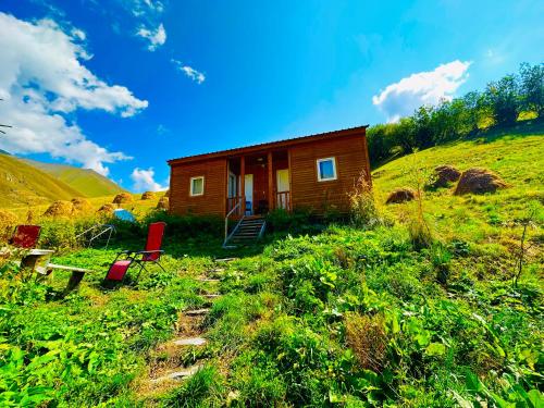 a small wooden cabin on a hill with two red chairs at amo-isuntke in Jut'a