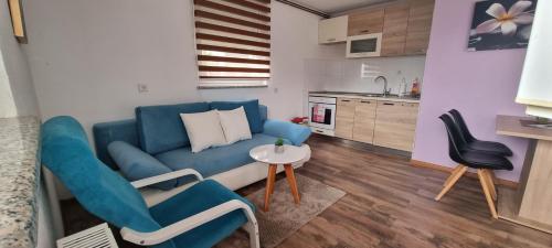 a living room with a blue couch and a table at Apartmani Bilić in Korenica