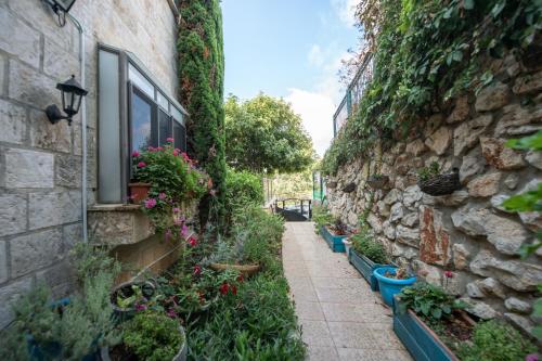 an alley with flowers and plants on a stone wall at הים פוגש את ההר- בית בלב הגליל Sea & Mount in Adamit