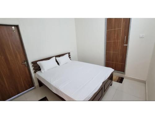 um pequeno quarto com uma cama e uma porta de madeira em Hotel Roopmati, Vidisha em Vidisha