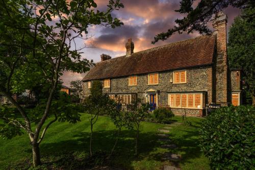 an old stone house with a tree in front of it at Walnut Tree House in Rustington