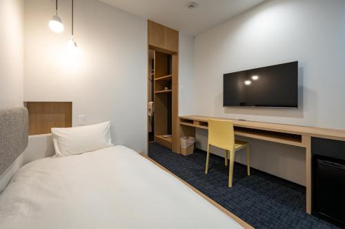 Cette chambre comprend un lit et un bureau avec une télévision. dans l'établissement plainn by negura, à Bungotakada