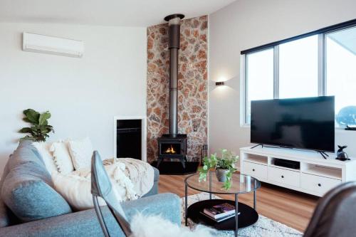 a living room with a couch and a tv at Shelly's Waterfront Property - Brand New in Kioloa