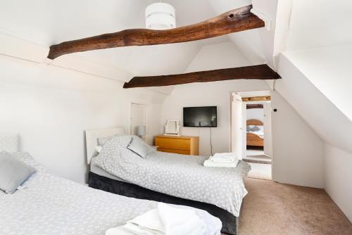 two beds in a room with white walls and wooden beams at Walnut Tree House in Rustington