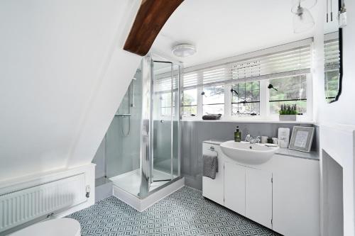 a white bathroom with a shower and a sink at Walnut Tree House in Rustington