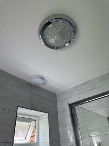 a ceiling light in a bathroom with a mirror at New Cozy Studio Apt. House with Parking. Entire space in Slades Green