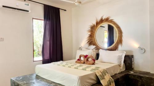 a bedroom with a bed with two teddy bears on it at Garden Beach Bungalows Jambiani in Jambiani