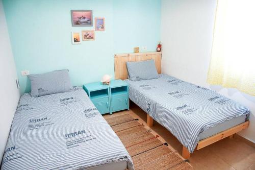 2 camas individuales en una habitación con una mesa azul en זמן מדבר, en Mitzpe Ramon
