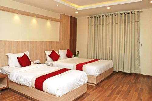 two beds in a hotel room with red pillows at Hotel Nilakantha Pvt. Ltd in Kathmandu