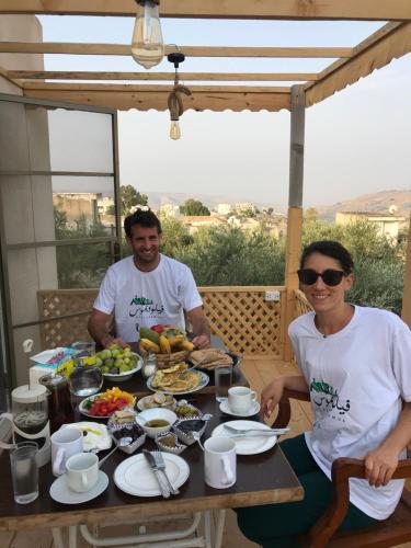 two people sitting at a table with food on it at Beit Philodemus in Um Qeis