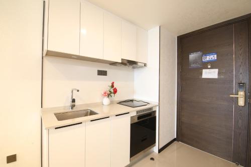 a kitchen with white cabinets and a sink and a door at Xinghe Times Apartment - Shenzhen North Railway Station in Shenzhen