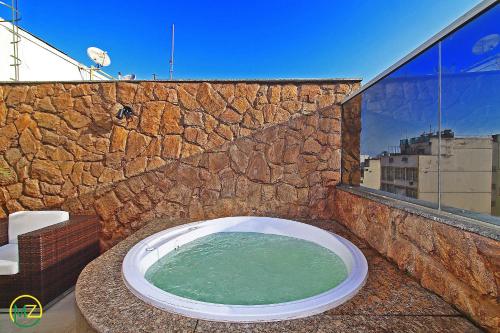 y baño con bañera en una pared de piedra. en Linda cobertura com jaccuzzi e terraço, en Río de Janeiro