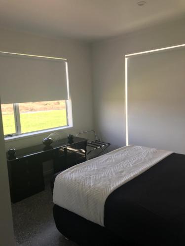 a bedroom with a bed and a desk and a window at Pukehina Retreat and Lodge in Pukehina