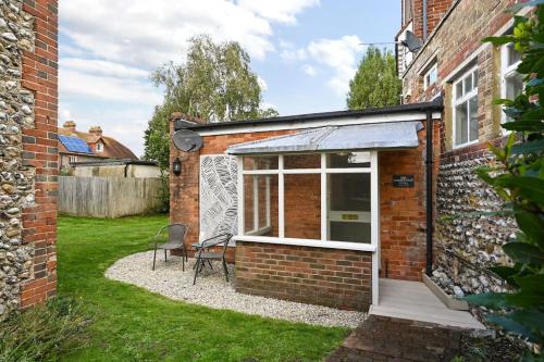 a small brick building with a window and a chair at Garden Flat, Walnut Tree House in Rustington