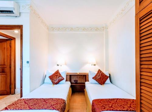 2 camas en una habitación con paredes blancas en Suite Bedroom Legian by DHMhotelier, en Seminyak