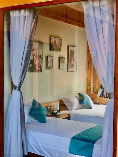 two beds in a room with blue curtains at Rosa Garden in Ninh Binh