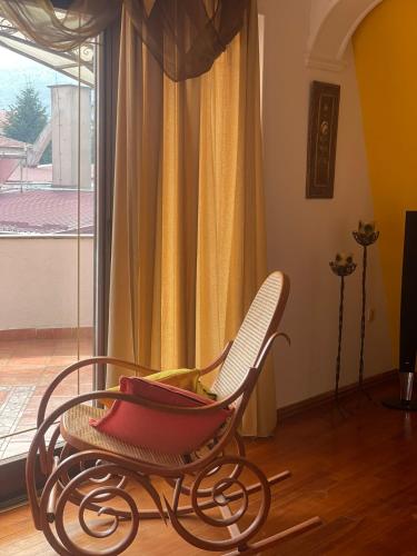 a red rocking chair in a room with a window at Central Exclusive Apartment/Penthouse in Bitola