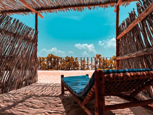 Pili Pili Uhuru Beach Hotel في جامبياني: أرجوحة على شاطئ به مظلة زرقاء