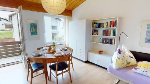 uma sala de jantar com uma mesa e uma estante de livros em Feriensiedlung True 7 em Scuol