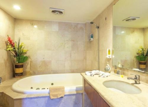 a bathroom with a tub and a sink at Suite Bedroom Legian by DHMhotelier in Seminyak