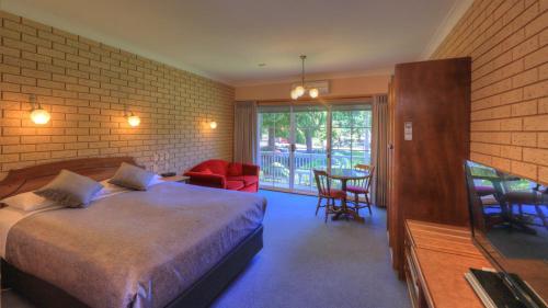 een slaapkamer met een bed en een tafel en stoelen bij Barrass's John Bright Motor Inn in Bright