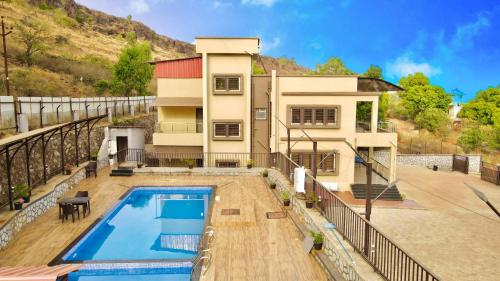 a house with a swimming pool in front of it at Aksha Villa in Panchgani