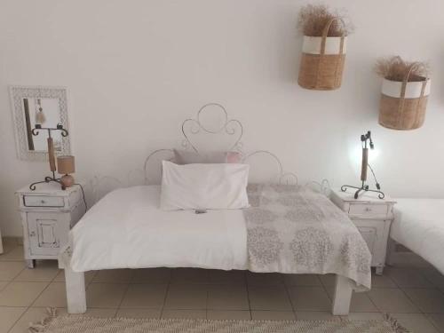 a white bedroom with a white bed and two night stands at Whimsical in Groutfontein
