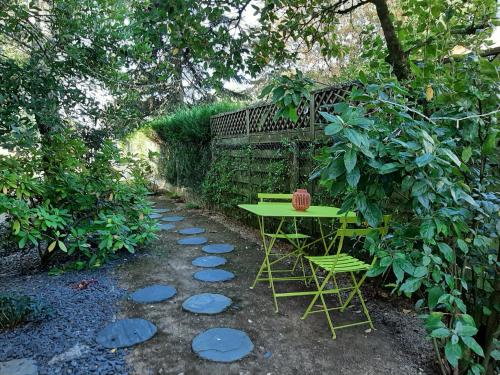a green table and two chairs in a garden at SAKURA in Fontaine-le-Comte