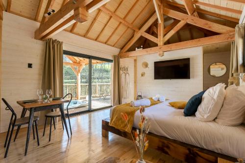 a bedroom with a bed and a table and a tv at Les Cabanes Suspendues in Satillieu