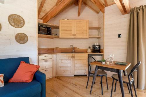 une petite cuisine avec une table et un canapé bleu dans l'établissement Les Cabanes Suspendues, à Satillieu