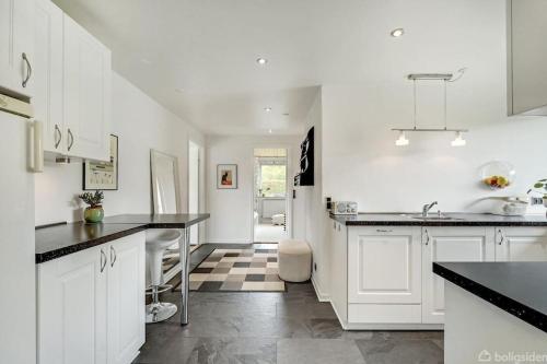 eine Küche mit weißen Schränken und schwarzen Arbeitsplatten in der Unterkunft Thuya Rica house (1.6km to Legoland) in Billund