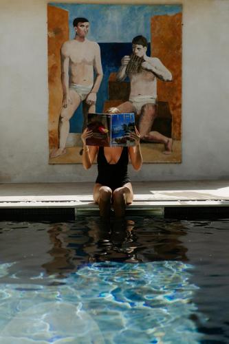 a woman sitting in the water holding a box at Oustau Camarguen Hôtel & Spa in Le Grau-du-Roi