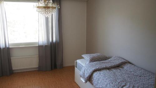 una camera da letto con un letto con un lampadario a braccio e una finestra di Lumi Room a Rovaniemi