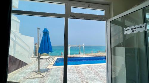 a view of a swimming pool through a glass door at Wadi Shab Beach Villa in Sur
