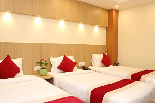 a hotel room with three beds with red pillows at Hotel Nilakantha Pvt. Ltd in Kathmandu