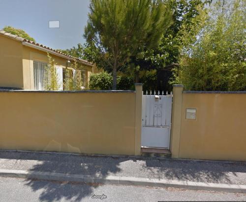 a yellow fence with a white gate in front of a house at COUDELIERES in Le Thor