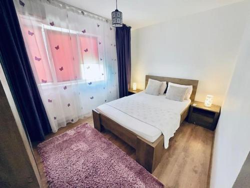 - une chambre avec un lit blanc et un tapis rose dans l'établissement Apartament in Regim Hotelier, à Bacău