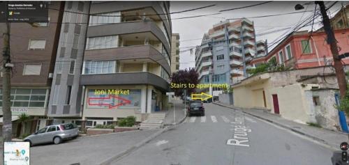 Una calle vacía con coches aparcados al costado de un edificio. en Mance Apartment, en Durrës