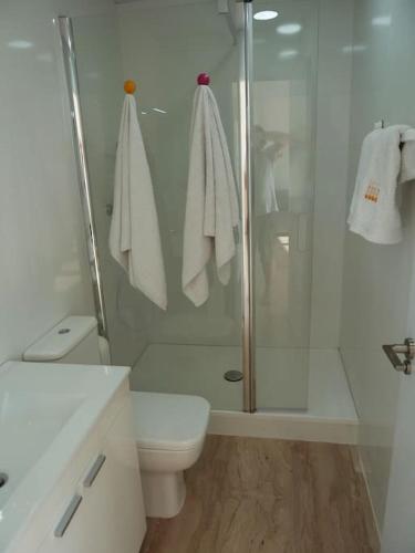 a white bathroom with a shower and a toilet at Bright loft near the sea + BIKES in Valencia