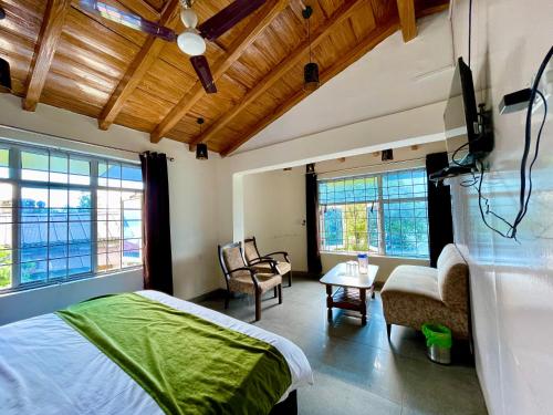a bedroom with a bed and chairs and windows at CENTRAL HOTEL by RB group Mall Road-prime-location in-front-of-naini-lake hygiene-and-spacious-room in Nainital