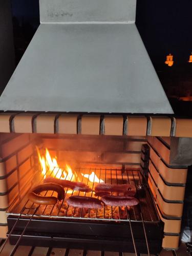 two sausages cooking in an oven with flames at Casa Rural La Gineta in Calaceite
