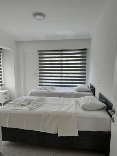 2 bedden in een witte slaapkamer met een raam bij Villa Selin in Ovacik