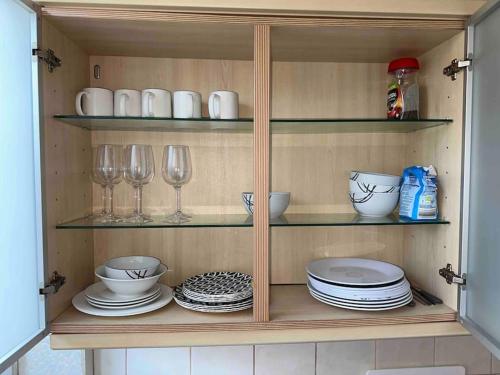 a cupboard with plates and glasses and dishes in it at Clevedon House in Manchester
