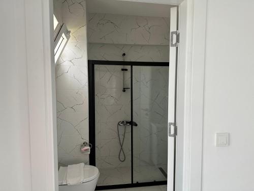 Un baño con inodoro y ducha de cristal. en Villa Selin, en Ovacık