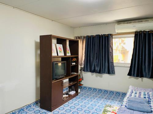 a living room with a tv and a book shelf at Condo popular T8 Fl.5 in Thung Si Kan