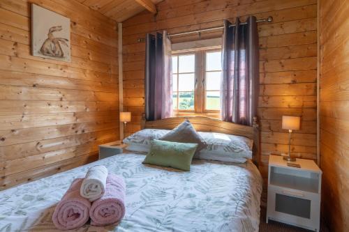a bedroom with a bed in a log cabin at Moor View Cabin (Oak Tree Lane) in Okehampton