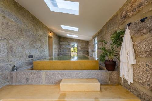 Un baño con paredes de piedra, bañera y sombrilla. en Lemon Villa-indoor pool, en Valpedre