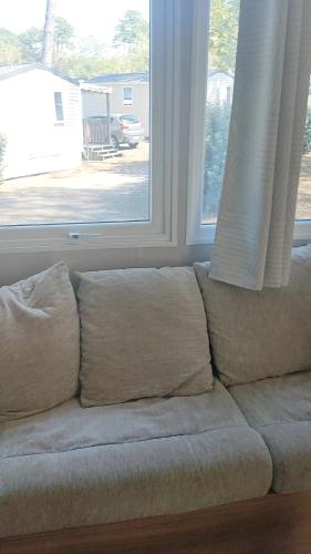 a couch with pillows sitting in front of a window at Mobil home spacieux in Seignosse