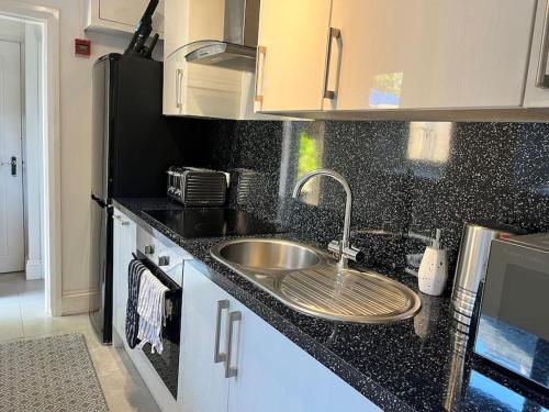 a kitchen with a sink and a black counter top at The Mews, private parking included, Windermere in Windermere