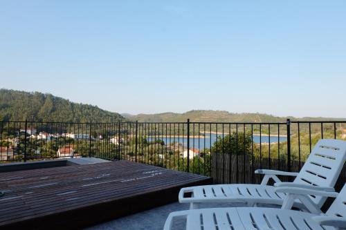 a deck with two chairs and a view of the water at Casa Rio, Amalia in Ferreira do Zêzere